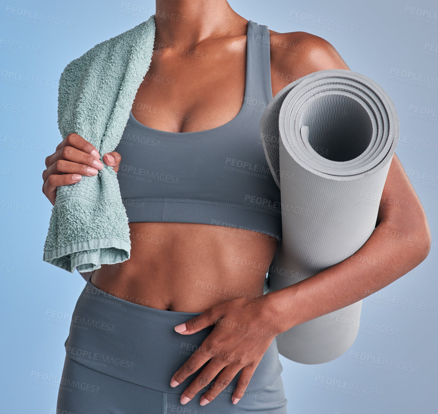 Buy stock photo Studio shot of a fit woman holding a towel and exercise mat against a grey background