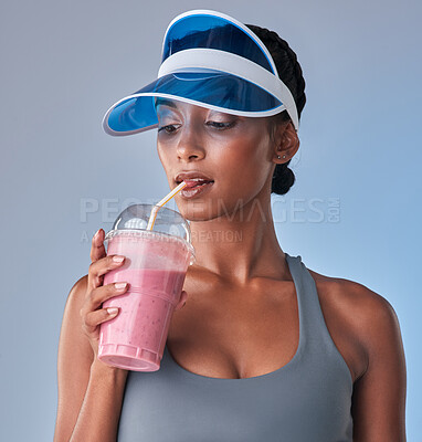 Buy stock photo Studio shot of a fit young woman having a healthy drink against a grey background