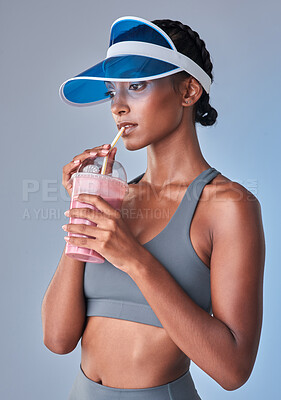 Buy stock photo Studio shot of a fit young woman having a healthy drink against a grey background