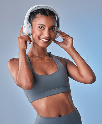 Buy stock photo Studio shot of a fit young woman using headphones against a grey background