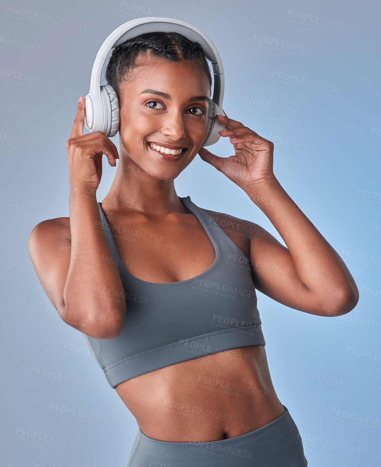 Buy stock photo Studio shot of a fit young woman using headphones against a grey background