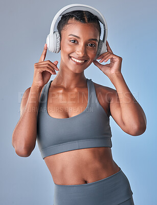 Buy stock photo Studio shot of a fit young woman using headphones against a grey background