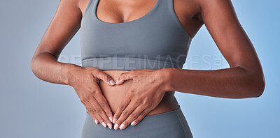 Buy stock photo Studio shot of a fit woman making a heart shaped gesture over her stomach against a grey background
