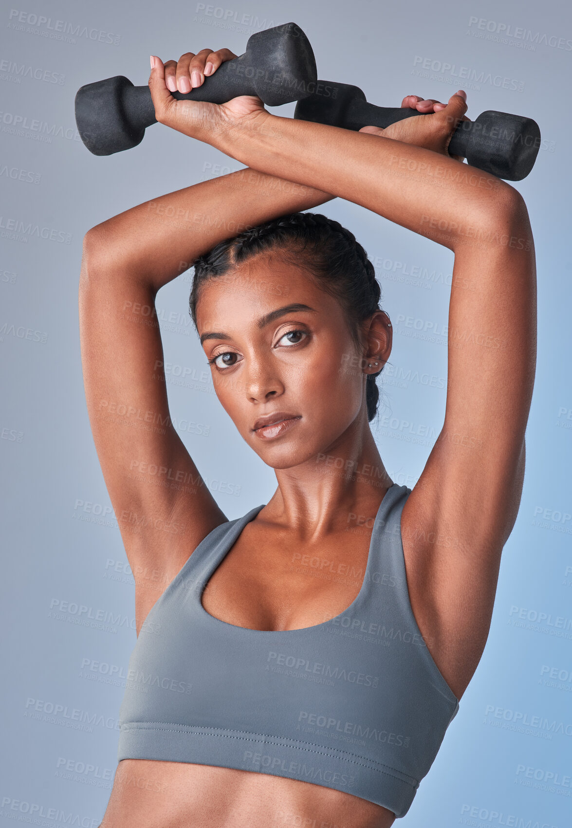 Buy stock photo Studio shot of a fit young woman working out with a dumbbell against a grey background