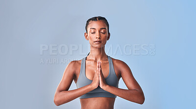 Buy stock photo Studio shot of a fit young woman meditating against a grey background