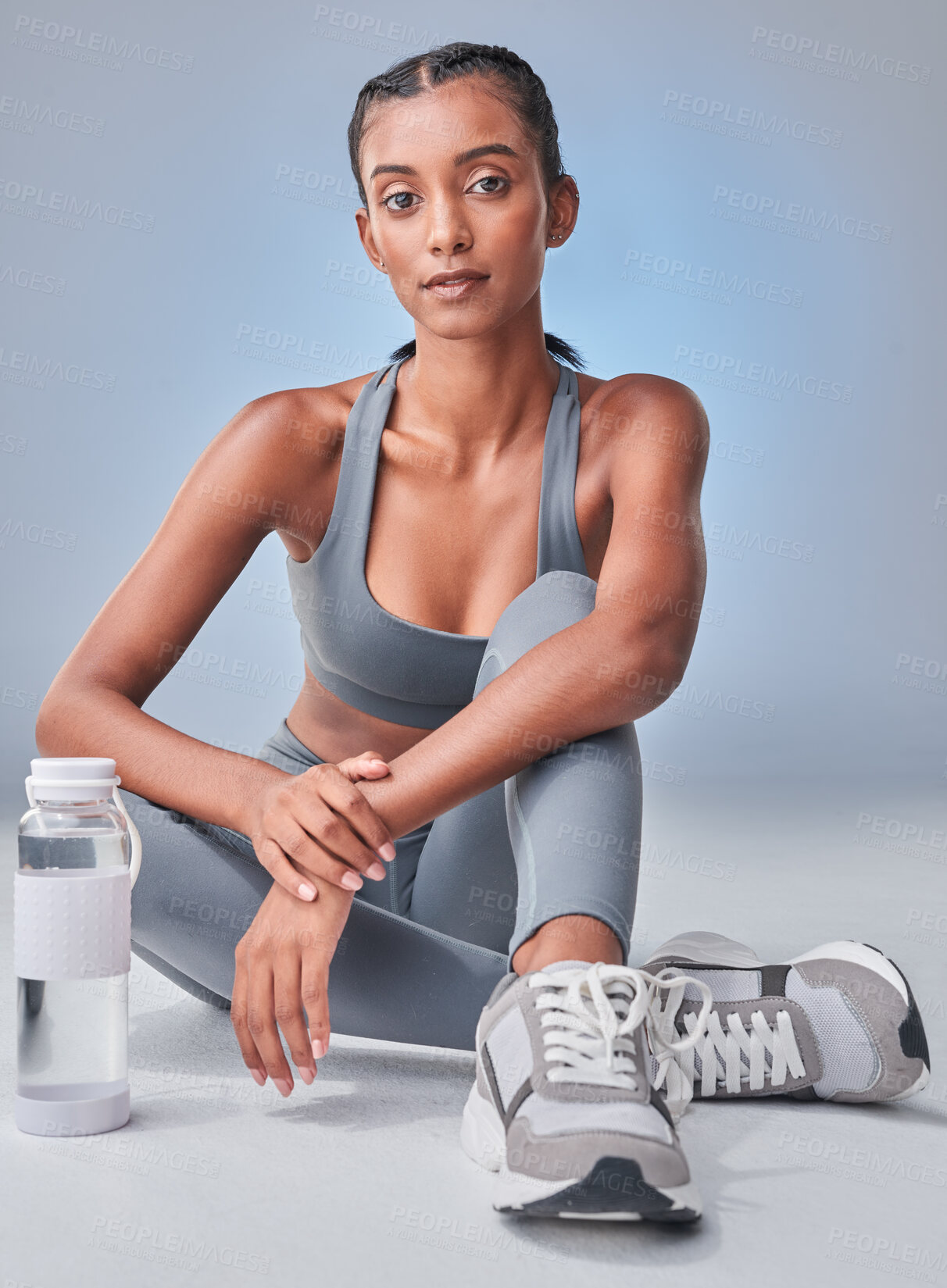 Buy stock photo Studio shot of a fit young woman drinking bottled water against a grey background