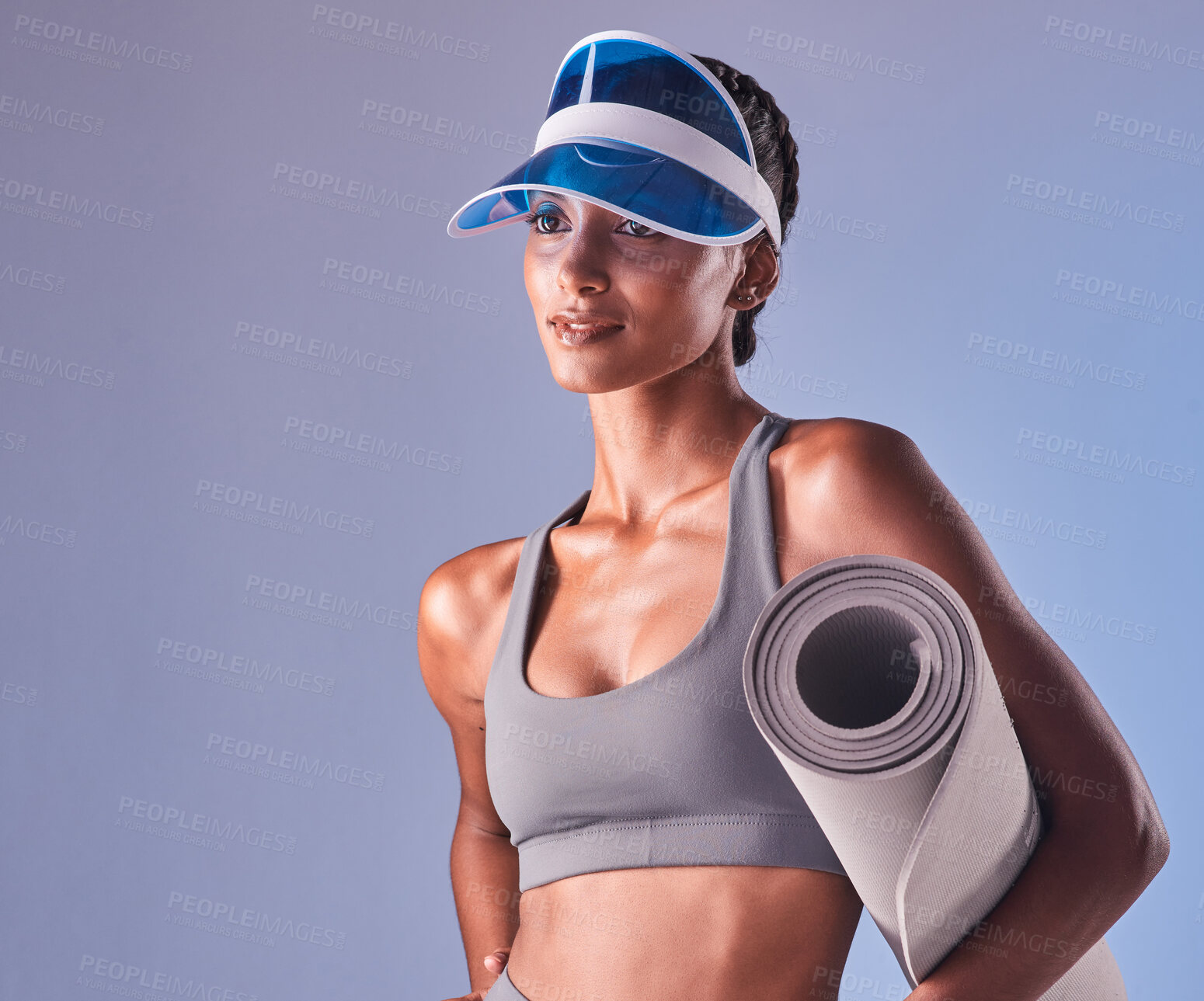 Buy stock photo Studio shot of a fit young woman holding a towel and exercise mat against a grey background