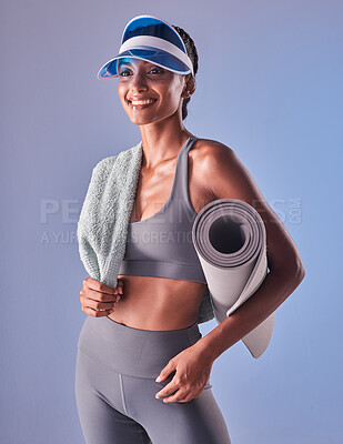 Buy stock photo Studio shot of a fit young woman holding a towel and exercise mat against a grey background