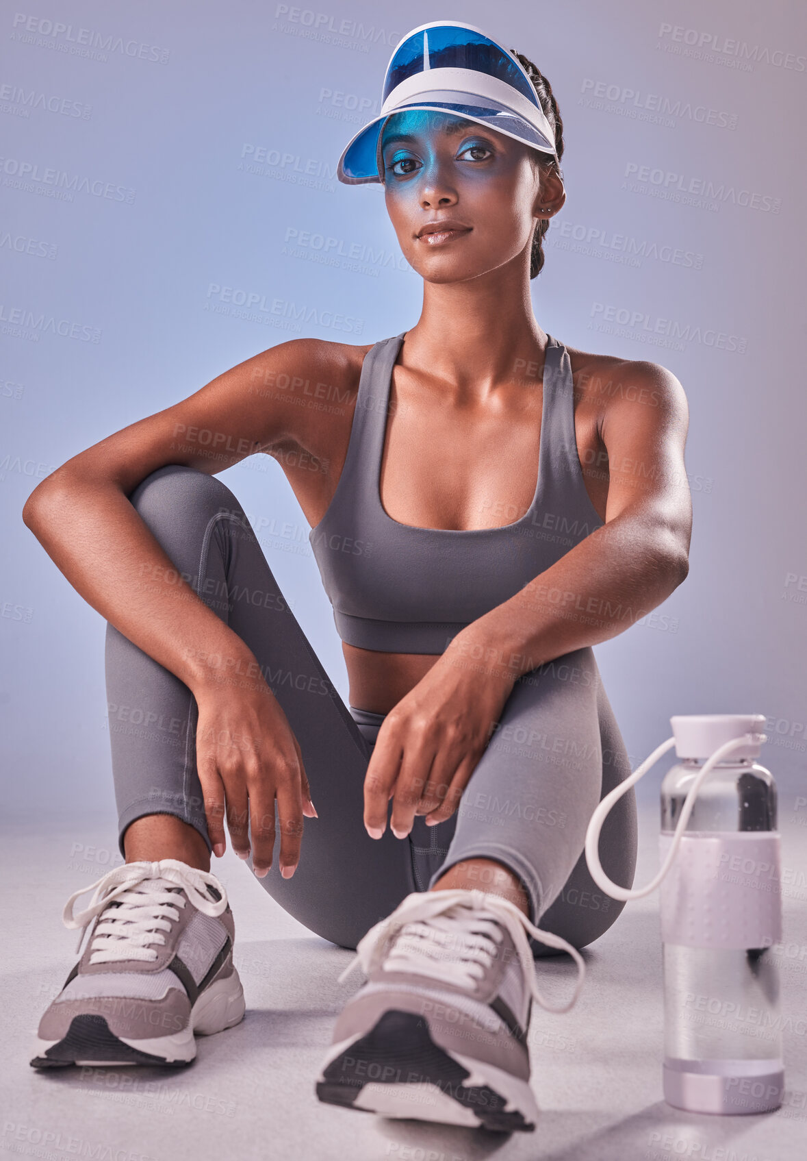 Buy stock photo Studio shot of a fit young woman drinking bottled water against a grey background