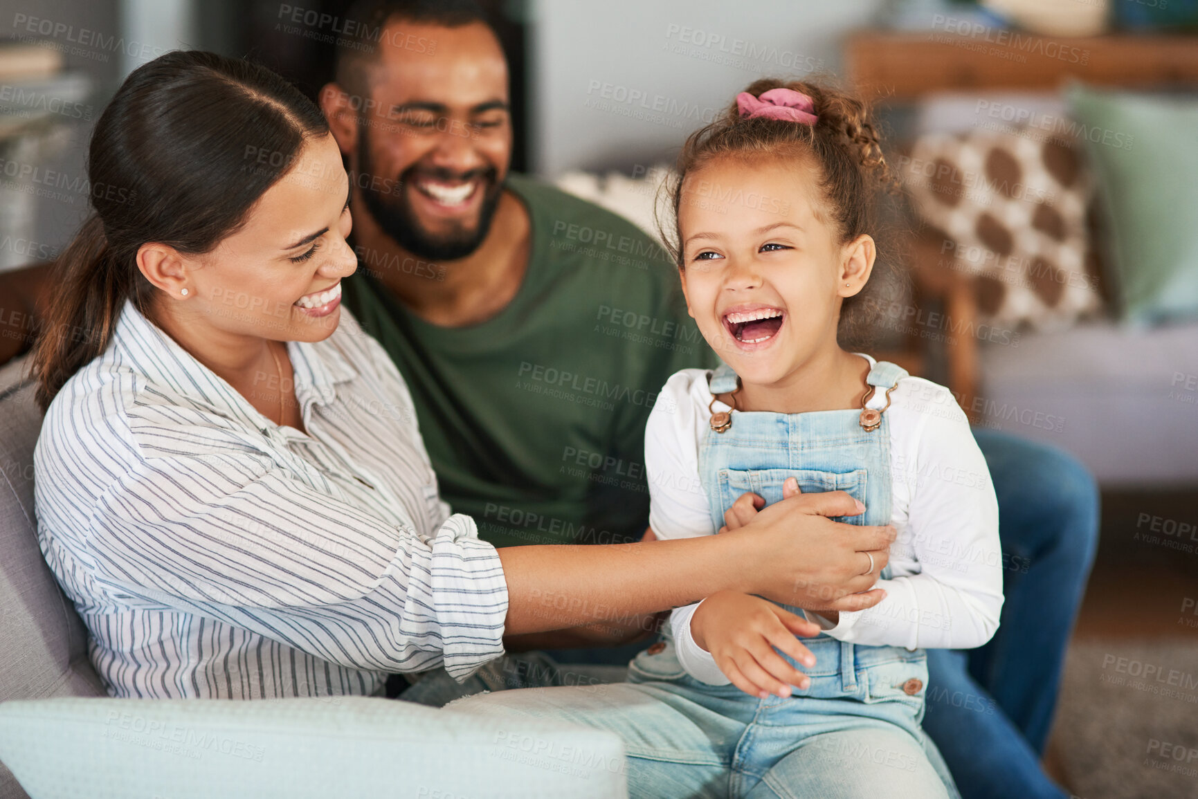 Buy stock photo Shot of a mother tickling her little daughter while relaxing together at home