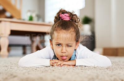 Buy stock photo Portrait of an adorable little girl making a face while lying on the floor at home