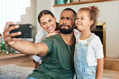 Buy stock photo Shot of a happy family making funny faces while taking selfies together at home