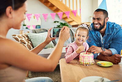 Buy stock photo Shot of a young mother taking a photo at her daughter's birthday celebration at home