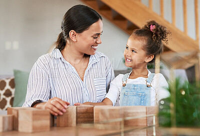 Buy stock photo Shot of a mother and her daughter playing with wooden blocks together at home