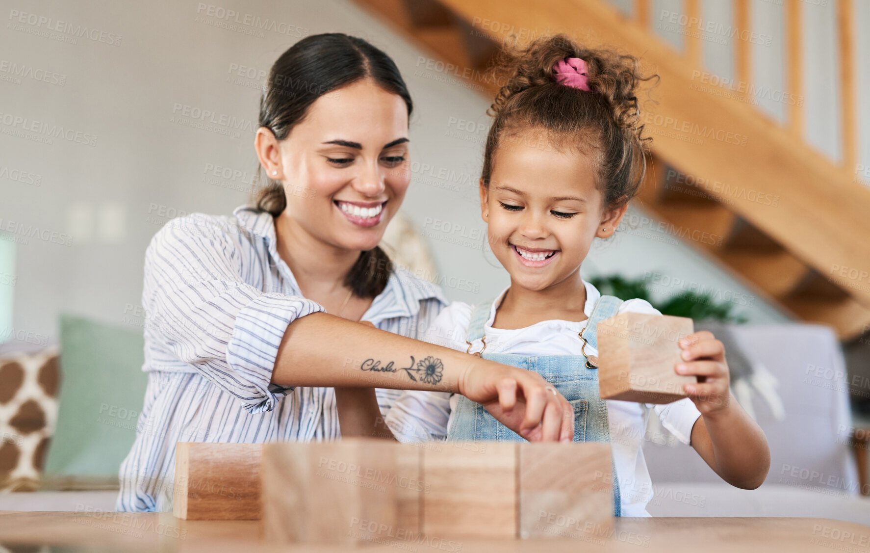 Buy stock photo Shot of a mother and her daughter playing with wooden blocks together at home