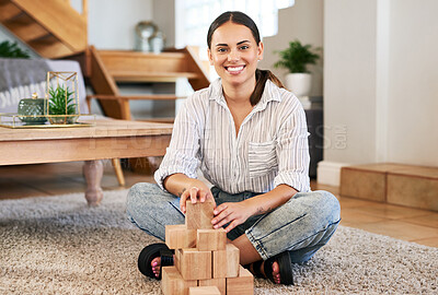 Buy stock photo Portrait of a young woman playing with wooden blocks at home