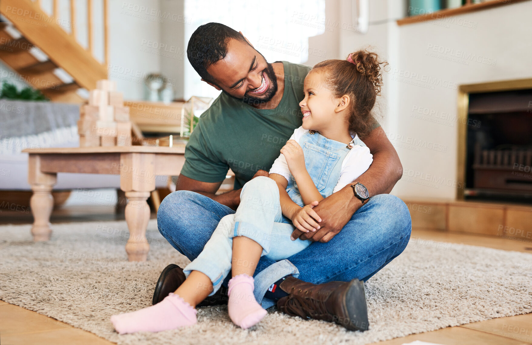 Buy stock photo Shot of a father tickling his little daughter while relaxing together at home