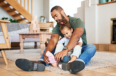 Buy stock photo Shot of a father helping his daughter put socks on her feet at home