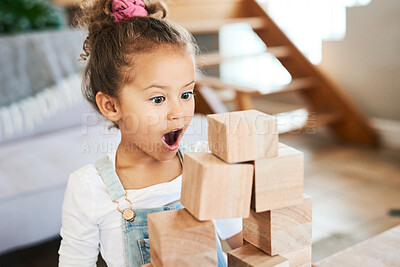 Buy stock photo Shot of an adorable little girl looking surprised while playing with wooden blocks at home