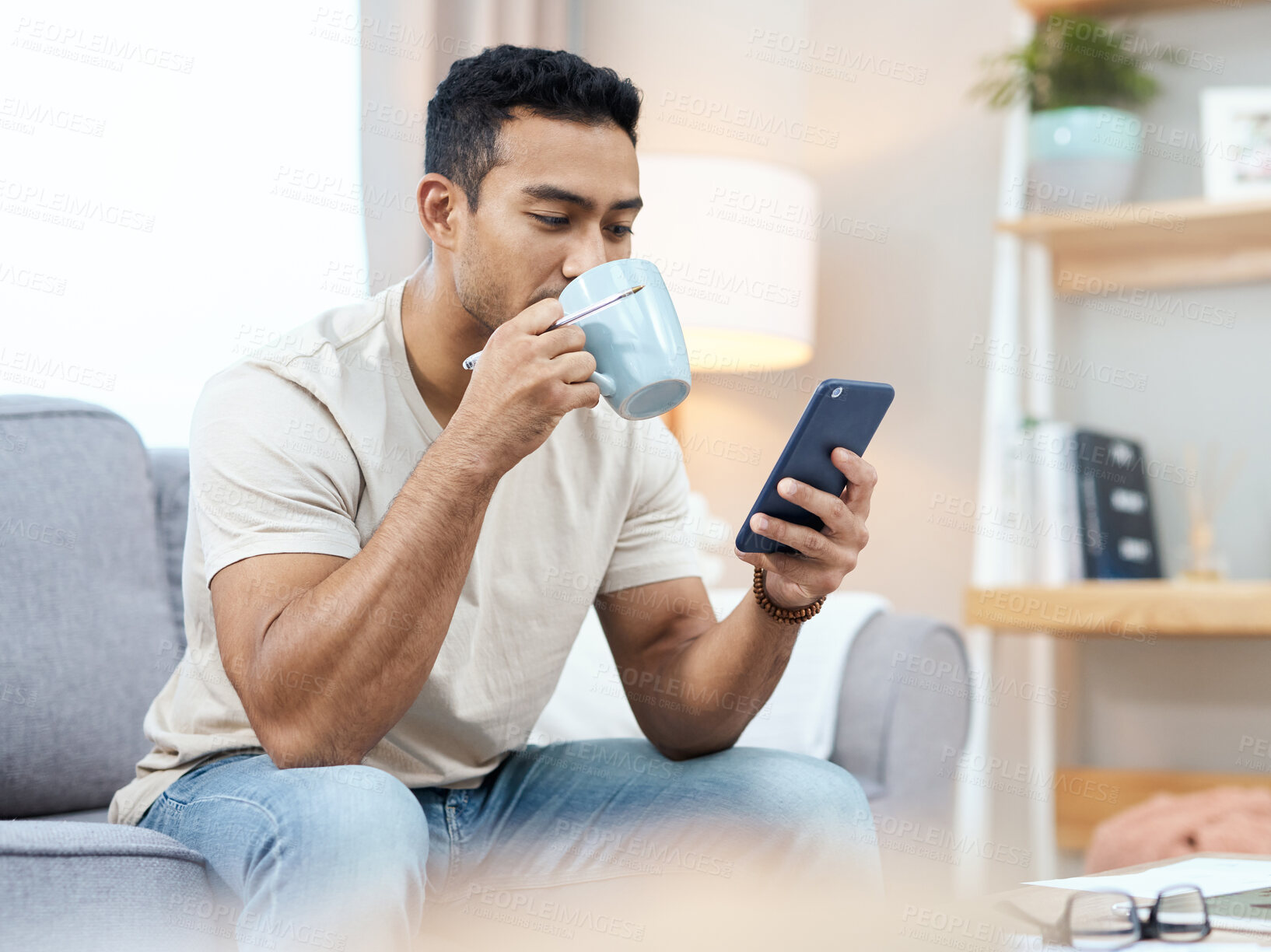 Buy stock photo Man, phone and texting with coffee on sofa in home for taste of hot beverage. Asian person, reading and mobile app for finance, message or planning on internet and social media by cellular with drink