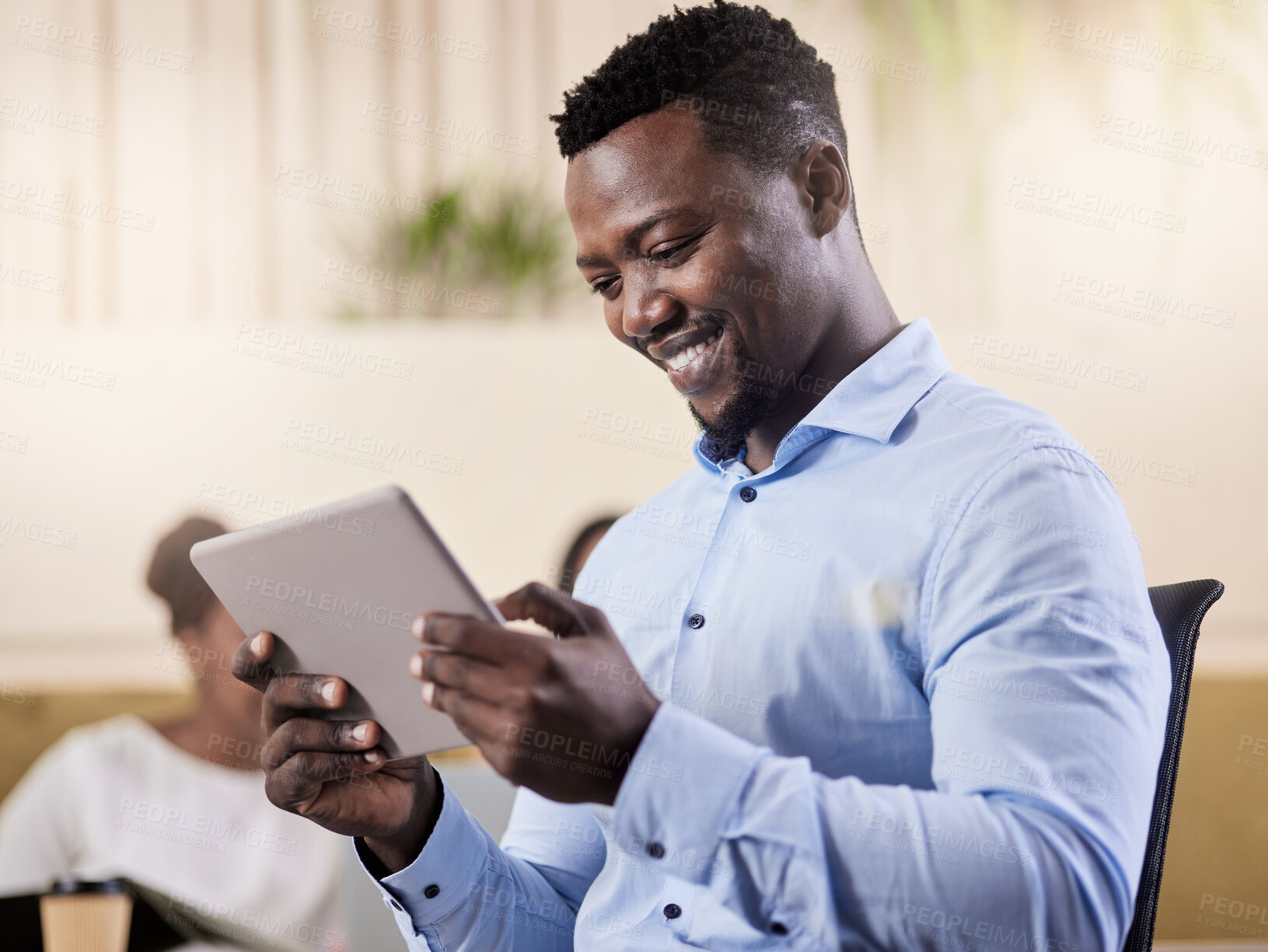 Buy stock photo Shot of a young businessman using his digital tablet while at work