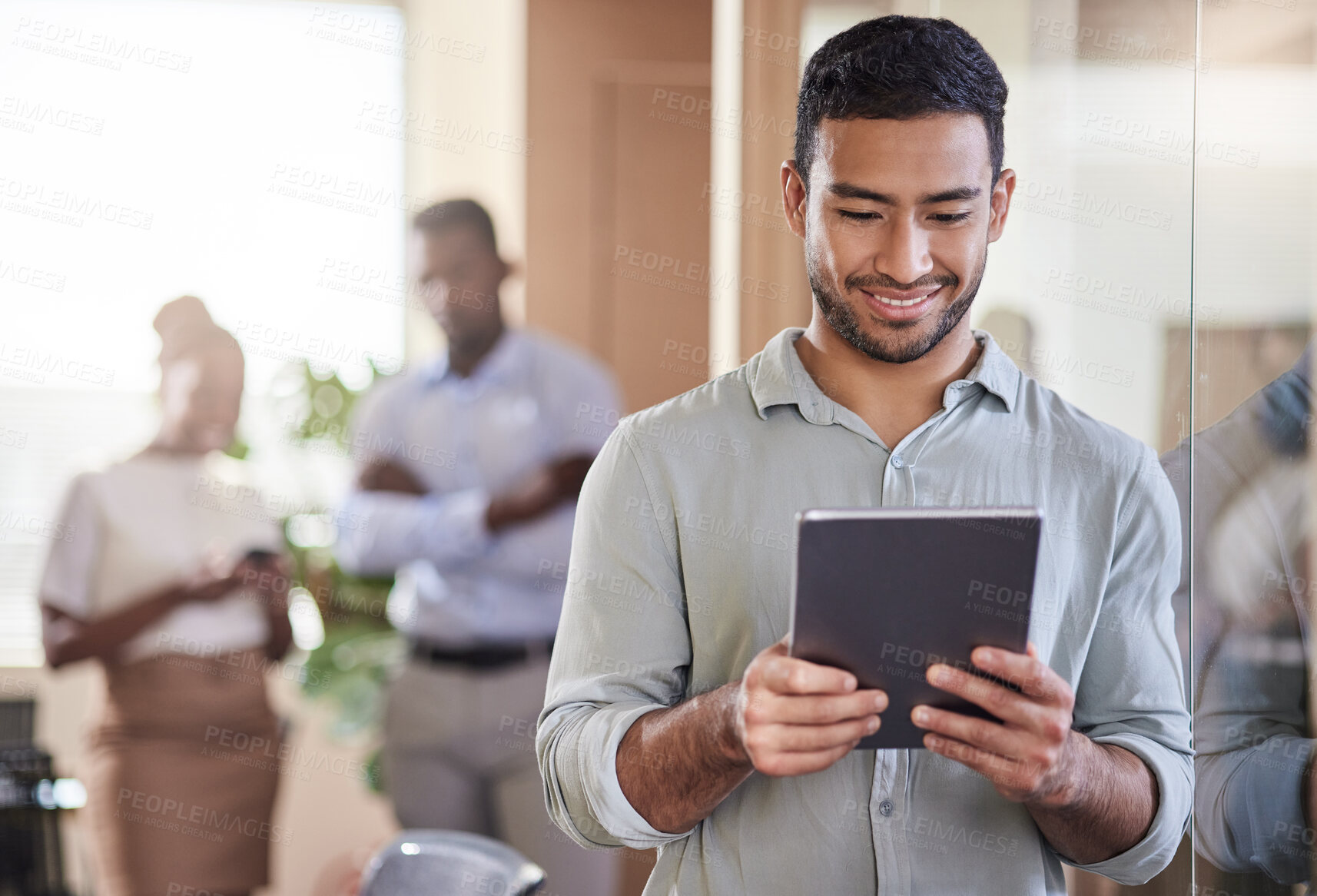 Buy stock photo Shot of a young businessman using his digital tablet at work