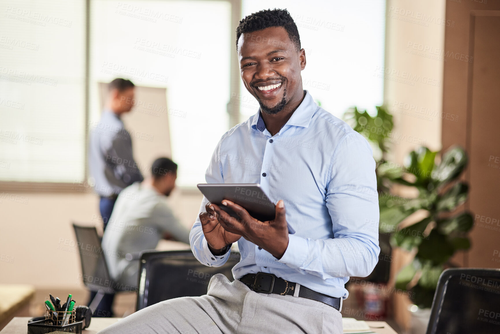 Buy stock photo Shot of a young businessman using his digital tablet at work