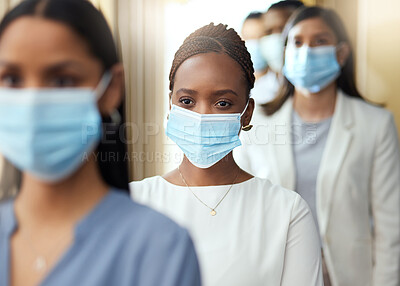 Buy stock photo Cropped shot of an attractive young businesswoman wearing a mask while standing in the middle of a queue in her office