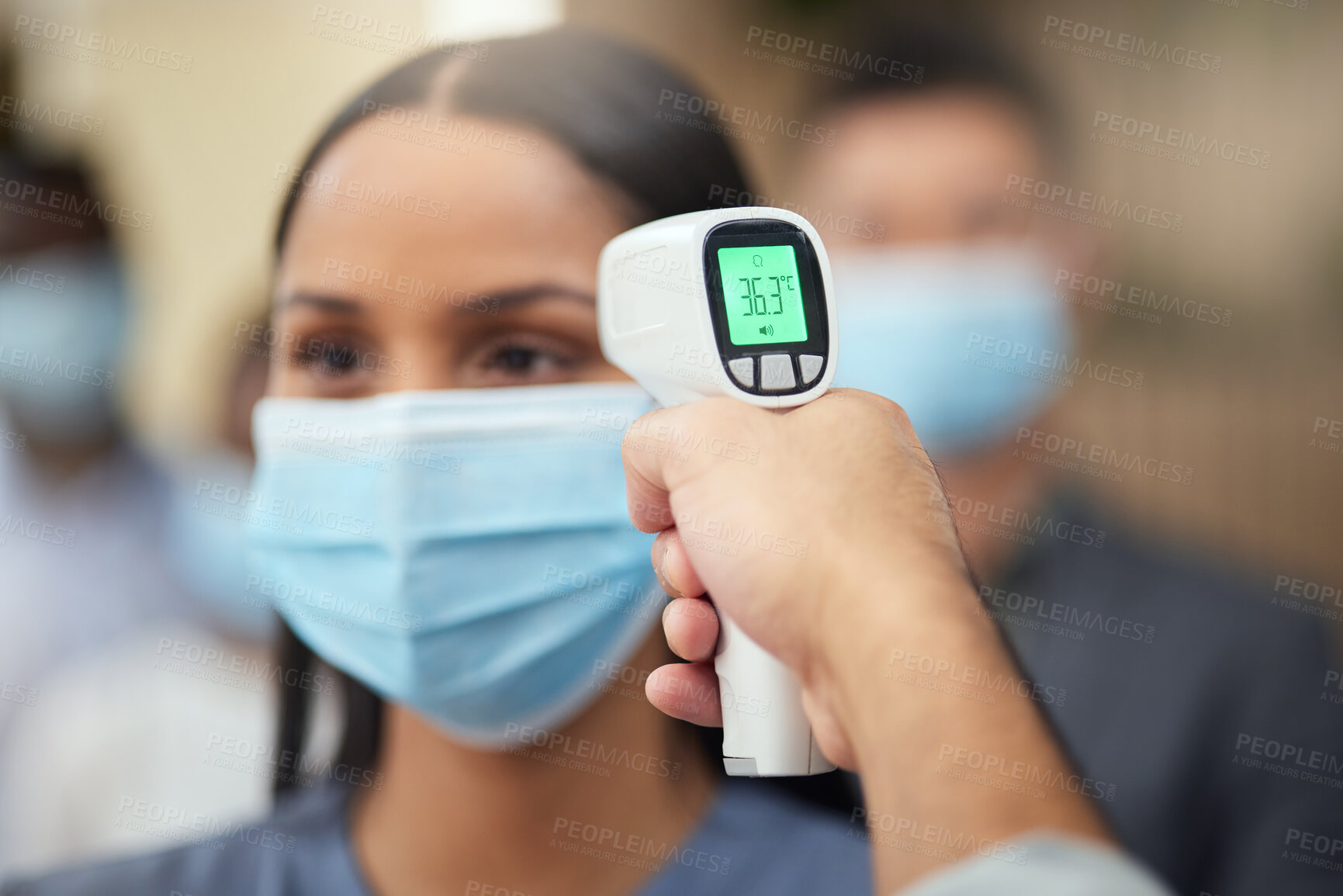 Buy stock photo Cropped shot of an attractive young businesswoman wearing a mask and having her temperature taken while standing at the head of a queue in her office