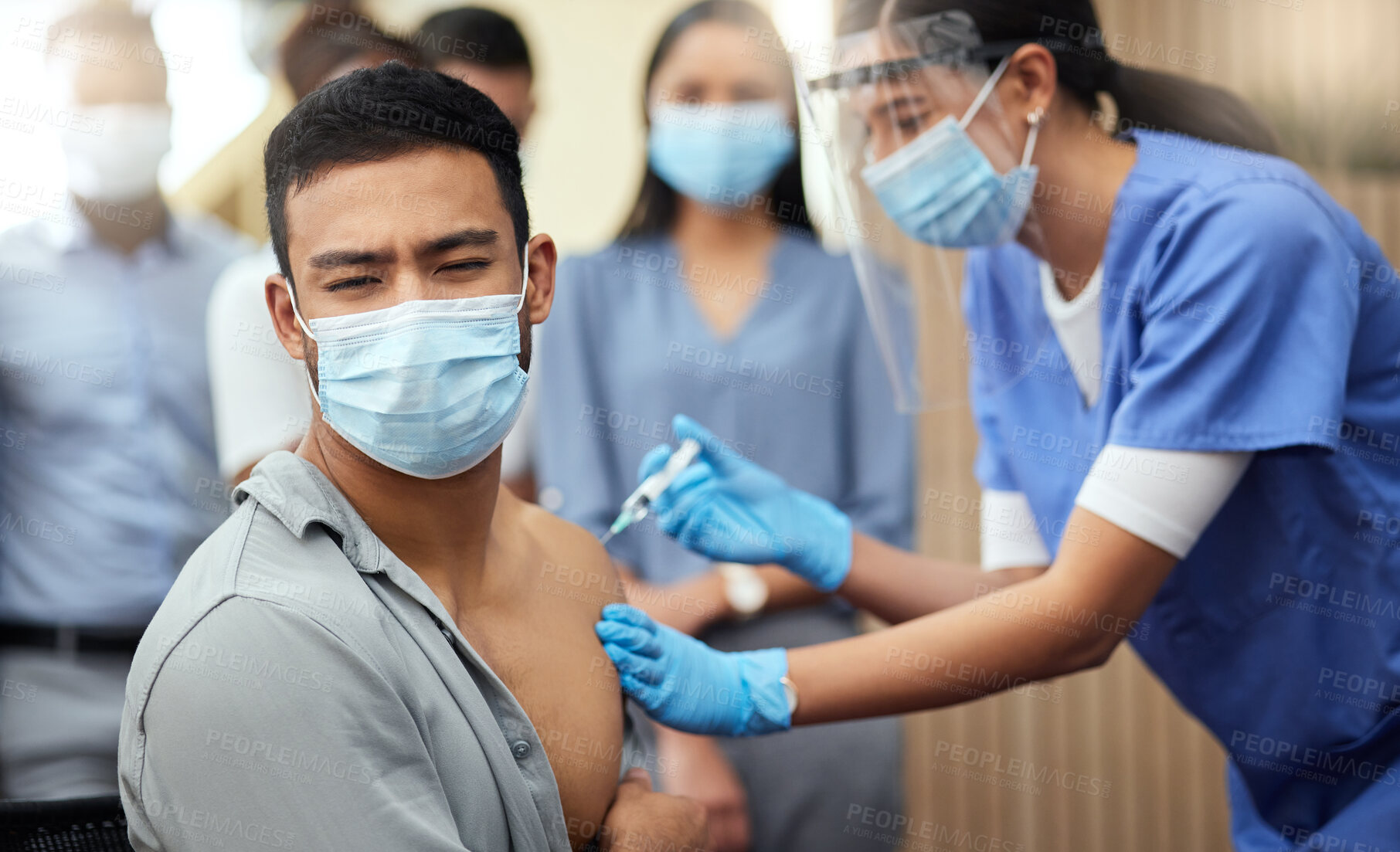 Buy stock photo Cropped shot of a handsome young businessman getting his covid vaccination from a female nurse in the office