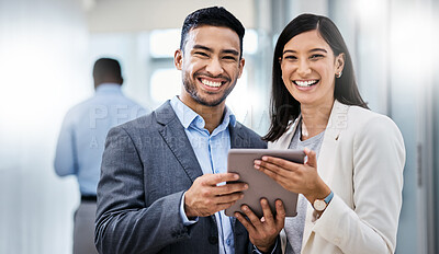 Buy stock photo Shot of two businesspeople standing together and holding a digital tablet in an office