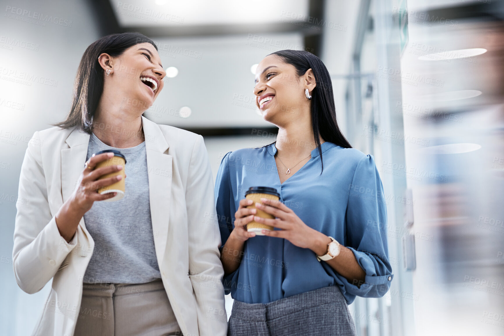 Buy stock photo Shot of two businesswomen holding coffees while talking in an office