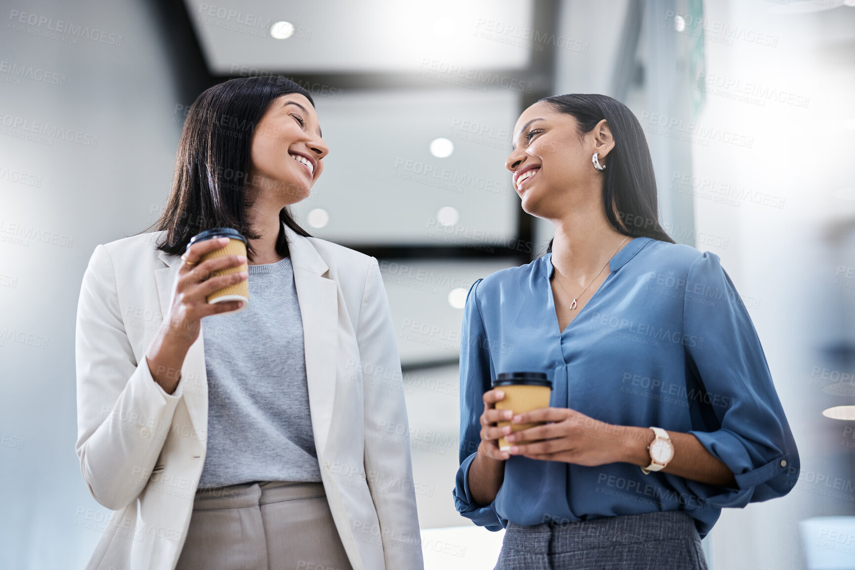 Buy stock photo Shot of two businesswomen holding coffees while talking in an office