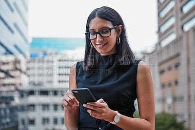 Buy stock photo Cropped shot of an attractive young businesswoman sending a text while standing outside on the office balcony