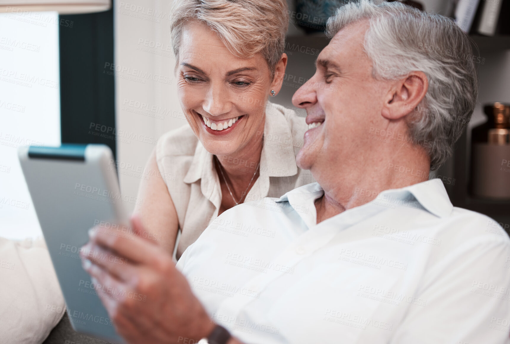 Buy stock photo Shot of a mature couple using a digital tablet at home on the sofa together