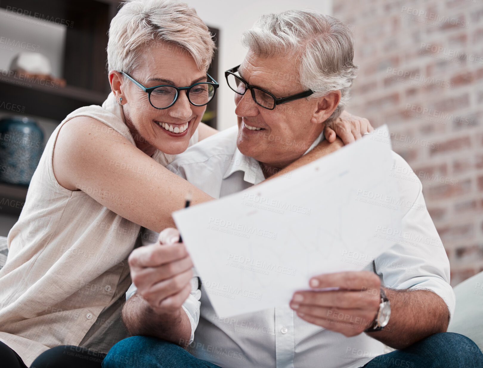 Buy stock photo Shot of a mature couple going through paperwork on the sofa at home together