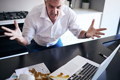 Buy stock photo Shot of a mature man feeling angry after spilling coffee on his paperwork and laptop in the kitchen at home