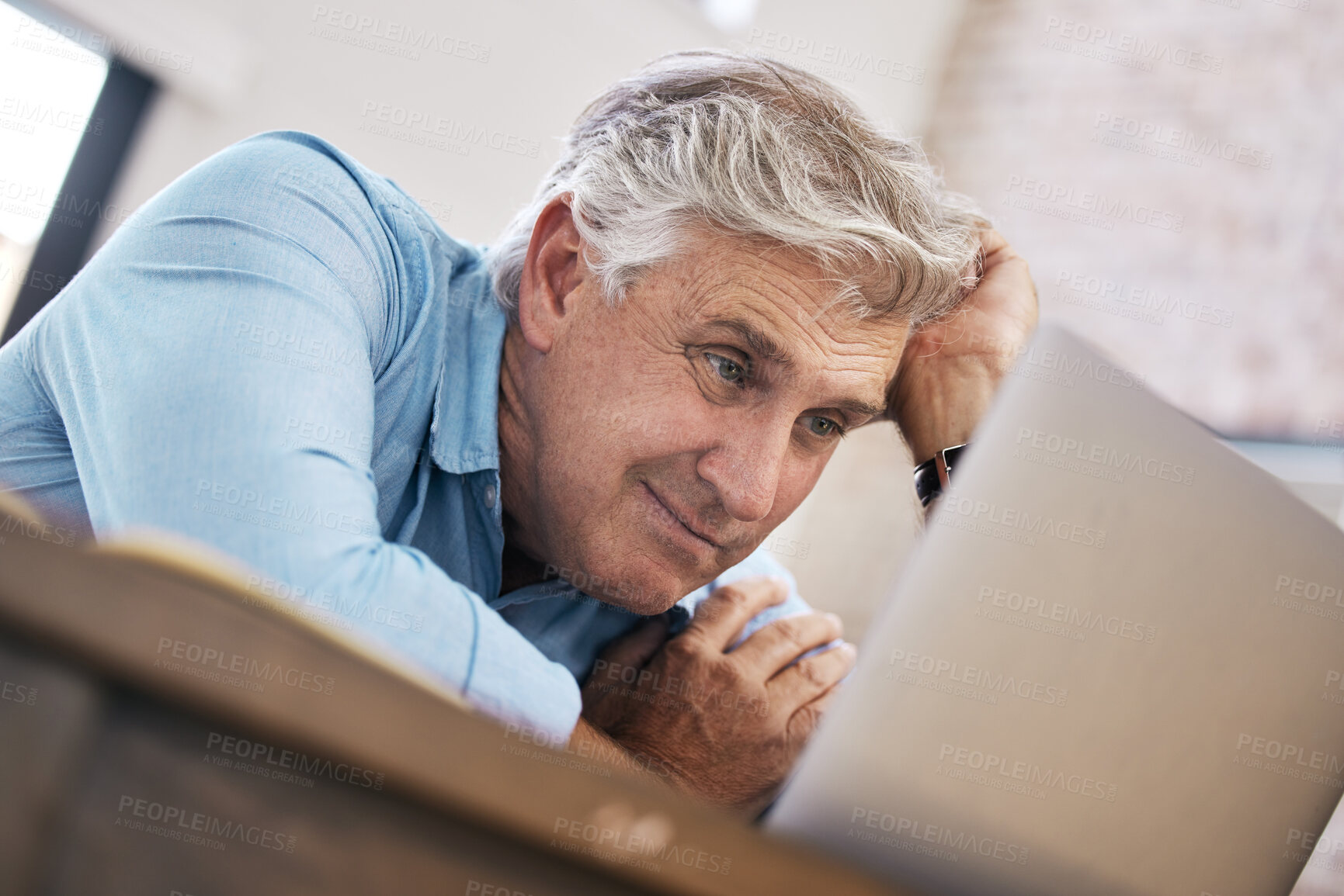 Buy stock photo Shot of a mature man sitting alone and feeling stressed while using his laptop to work from home