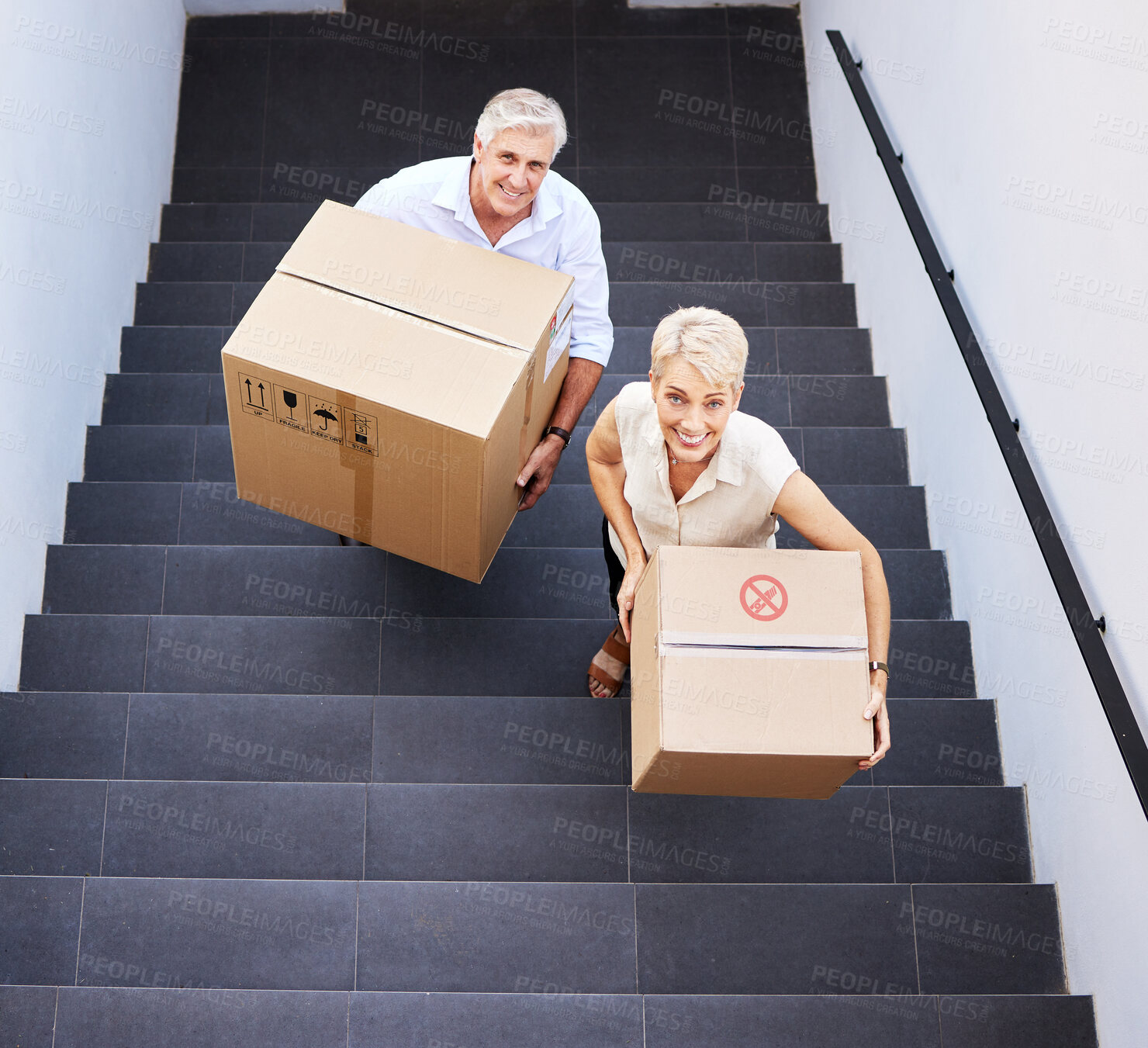 Buy stock photo Shot of a mature couple carrying boxes up the stairs on moving day