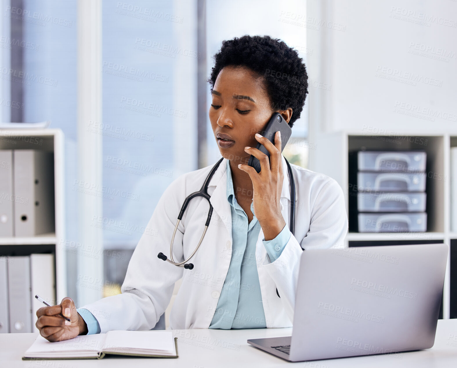 Buy stock photo Laptop, notebook and phone call with doctor black woman in hospital office for appointment. Computer, schedule and writing with medicine professional in cardiology clinic for healthcare or contact