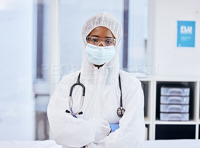 Buy stock photo Cropped portrait of a confident female doctor standing with her arms folded while dressed in PPE overalls in the office