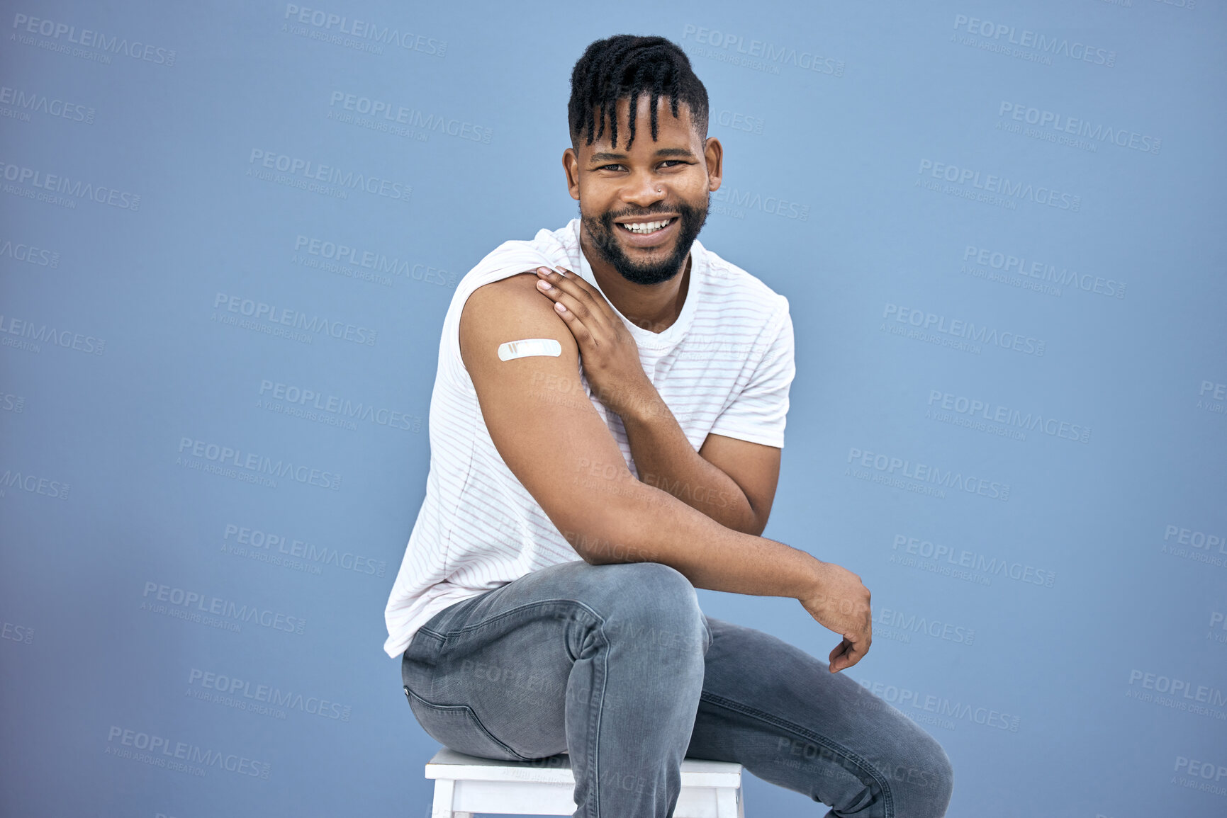 Buy stock photo Shot of a handsome young man sitting alone in the studio after getting his Covid vaccine