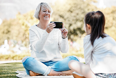 Buy stock photo Shot of a grandmother taking photos of her granddaughter outdoors