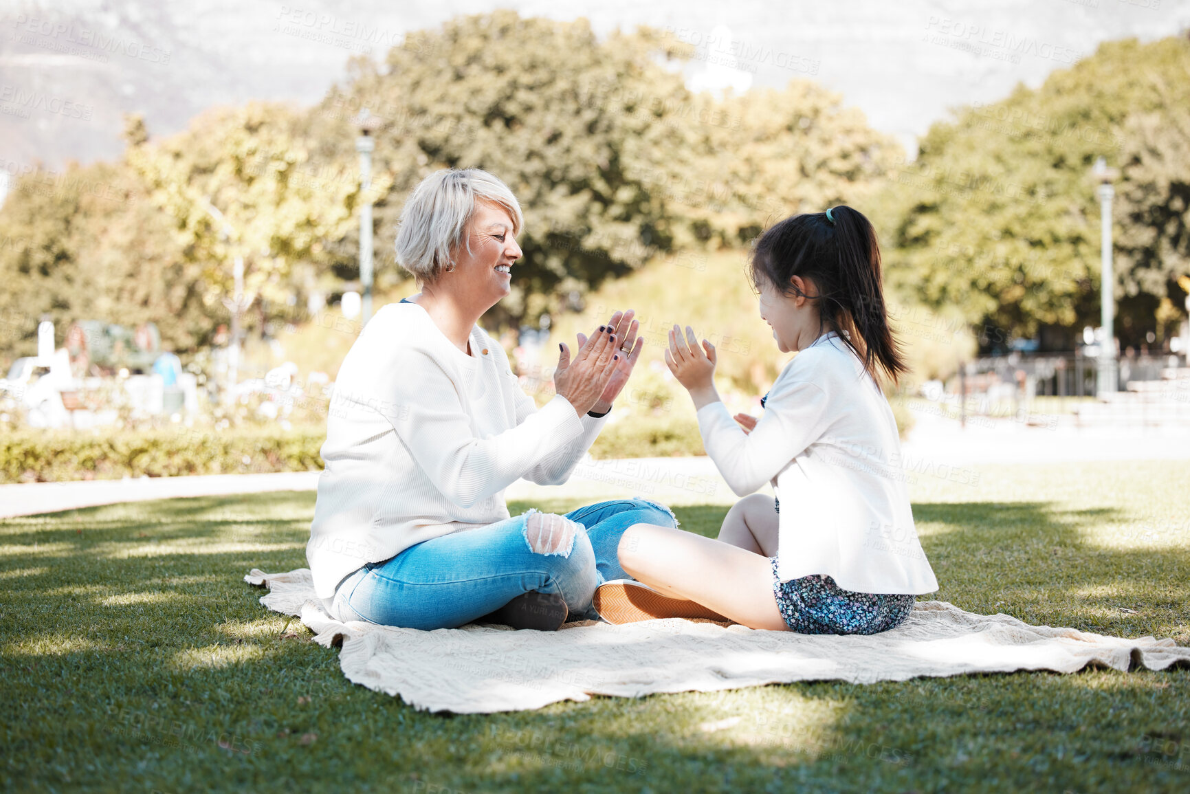 Buy stock photo Family, game or pattycake with grandmother and child outdoor on grass lawn together for bonding. Love, smile senior woman with girl grandkid at park for picnic, retirement or break in summer