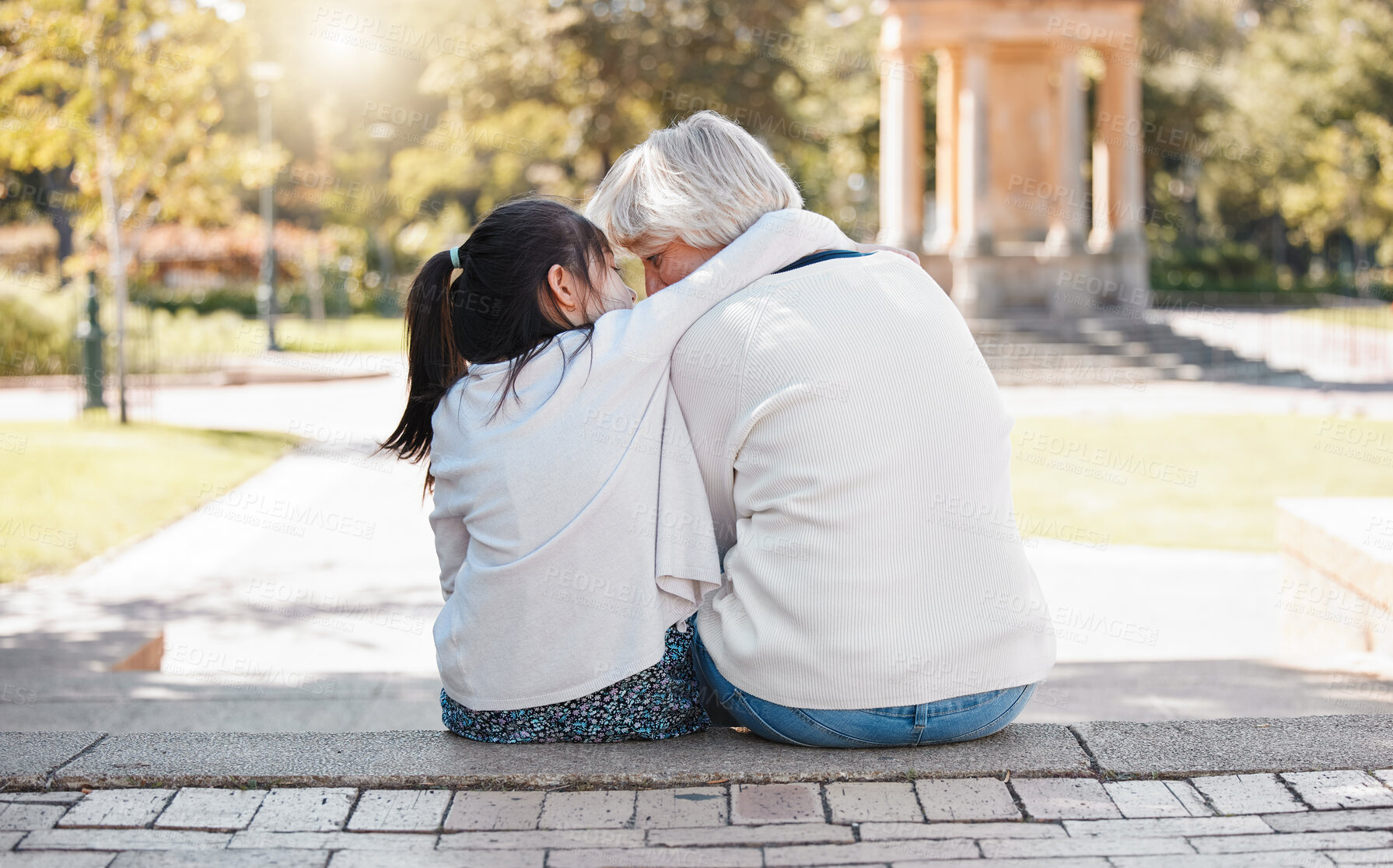 Buy stock photo Girl, grandmother and hug in the outdoor for trust or secret in family with grass and sunshine. Kid, hugging and grandma with back of together at the park with a whisper in summer to relax in nature.