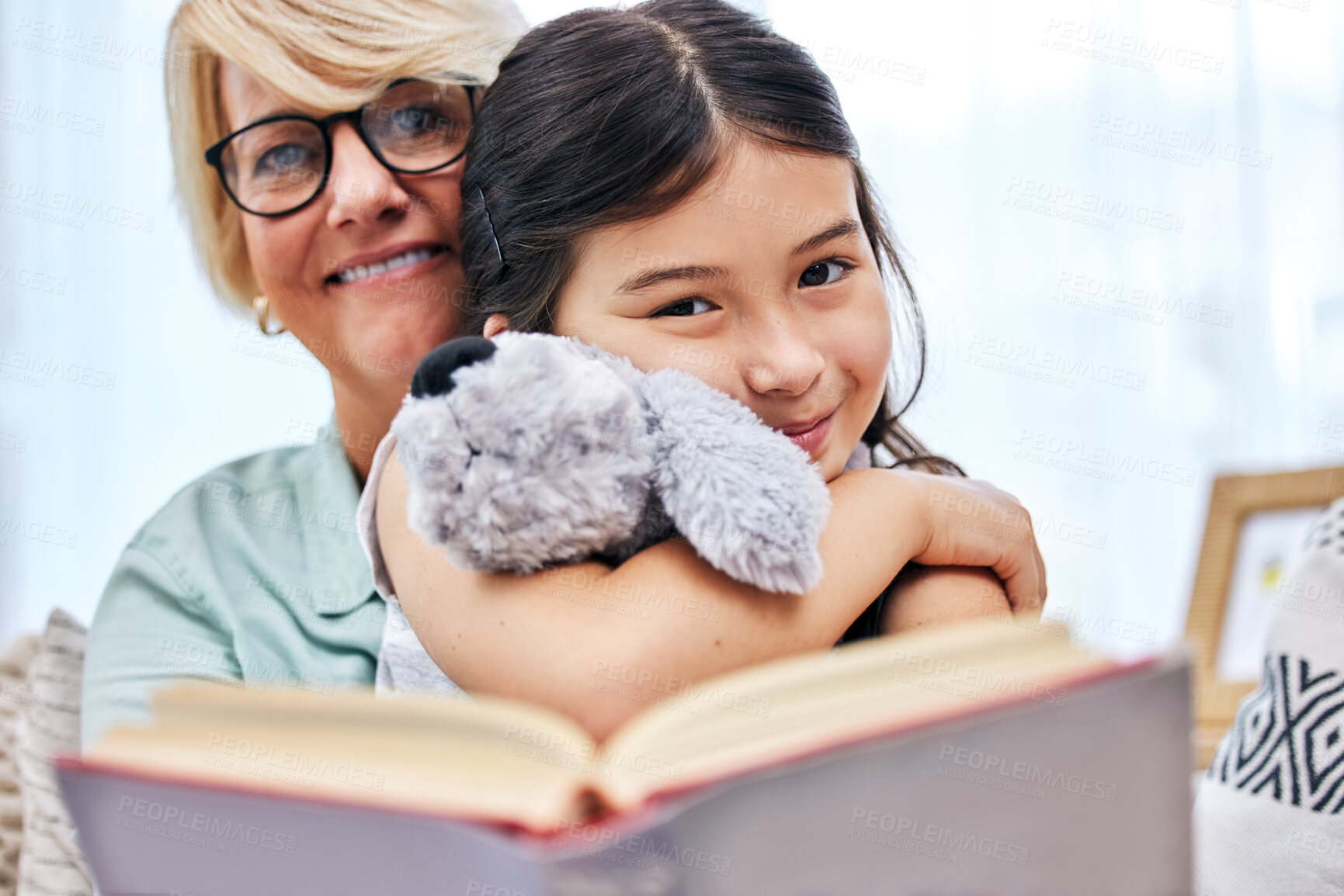 Buy stock photo Portrait, book and senior woman with child reading for knowledge with teddy bear at home together. Smile, bonding and elderly grandmother relax and enjoying story with girl kid holding toy at house.