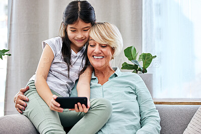 Buy stock photo Grandmother, child and cellphone in home for online, development and happy together on couch. Girl, woman and family on sofa with technology for gaming, live streaming  and love with smile for bond