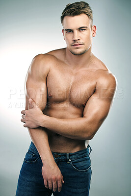 Buy stock photo Studio shot of a handsome young man posing shirtless against a grey background