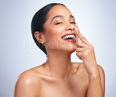 Buy stock photo Portrait of an attractive young woman applying moisturiser against a grey background