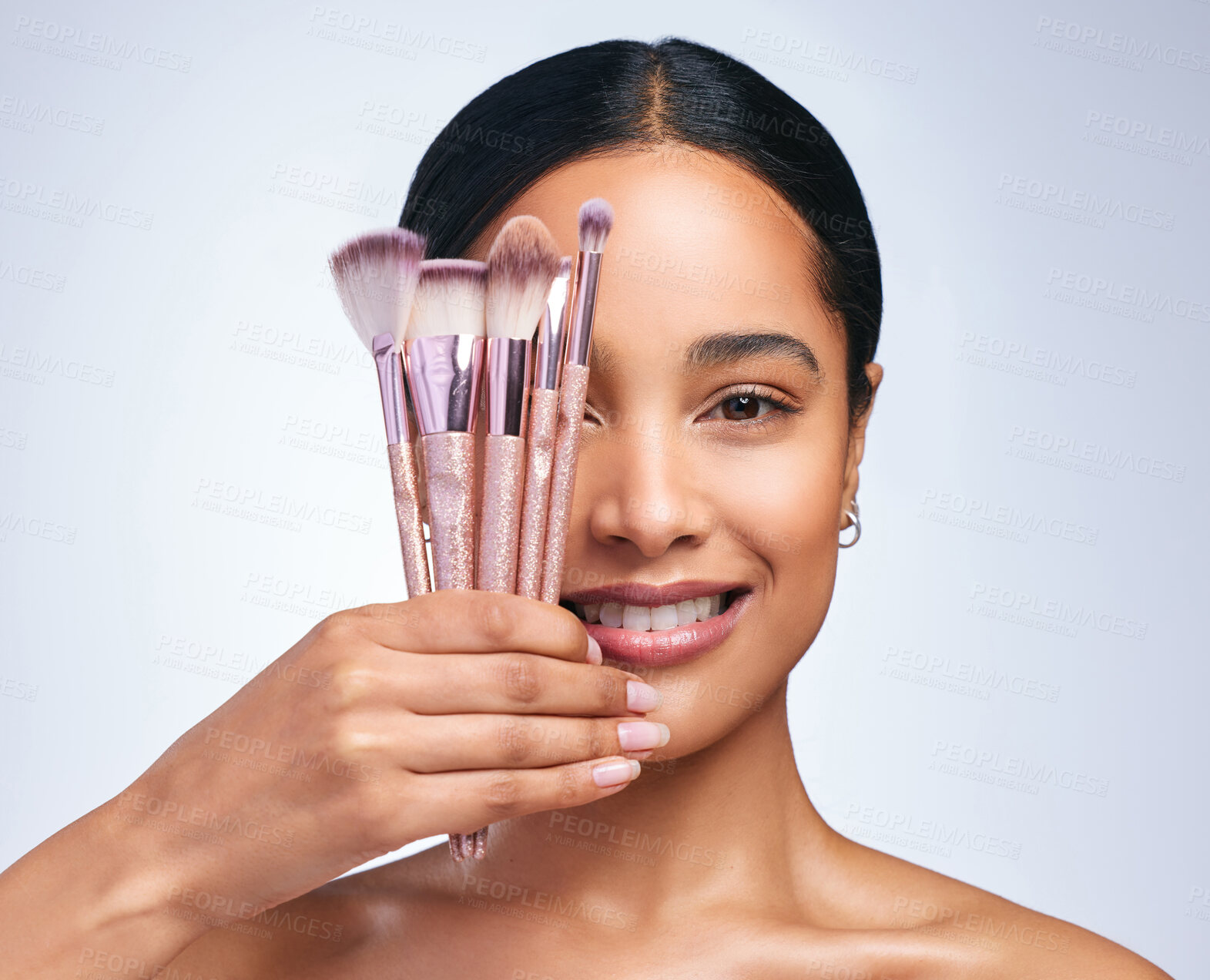 Buy stock photo Shot of a young attractive woman applying makeup against a grey background